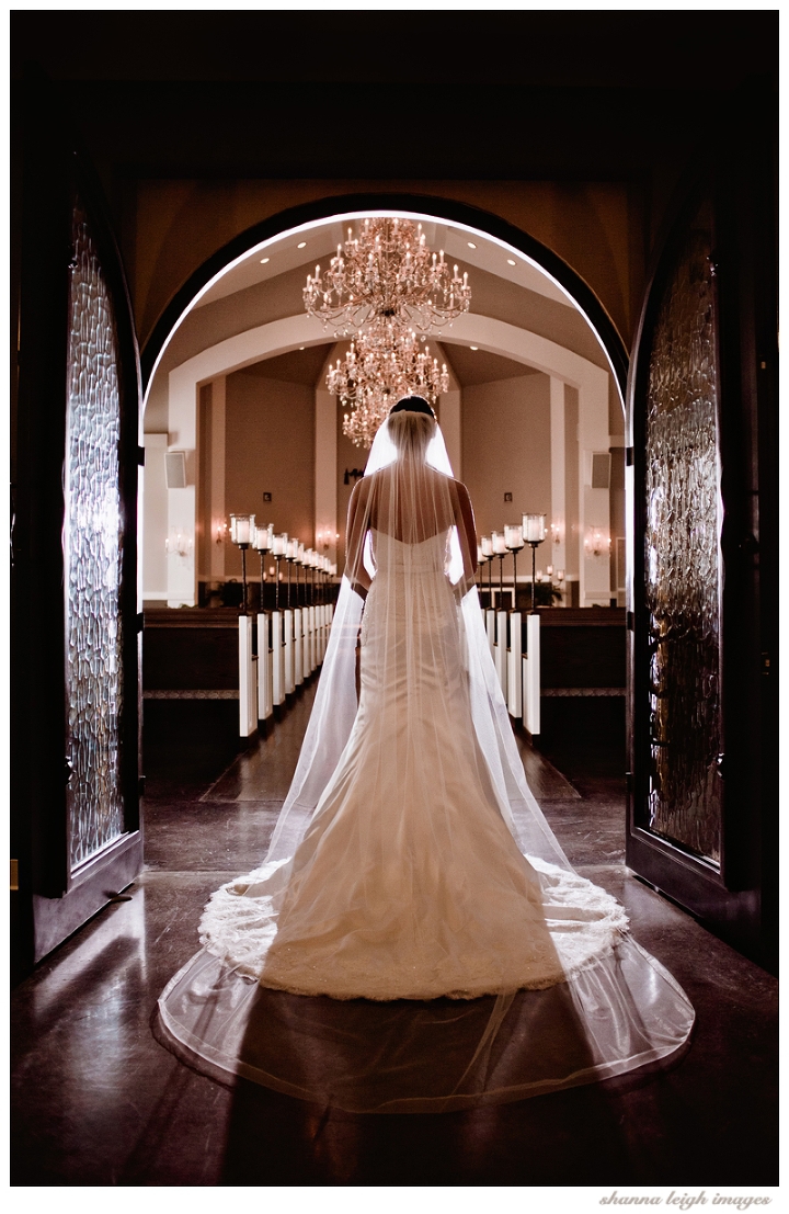 Jennifer walking through the doors of the chapel for her bridal portraits at her gorgeous mediterranean style wedding venue, the Piazza in the Village in Colleyville, Texas.