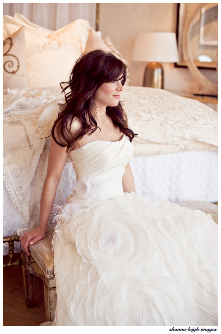 Beautiful bride Emily in her custom wedding dress by Bliss Bridal of Fort Worth, Texas posing for her bridal portraits at the gorgeous vintage styled Iron Bed store in Frisco, Texas with her beautiful brunette loose curls.