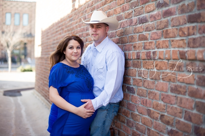 Lisa and Josh posing for maternity portraits in a brick alley in downtown Roanoke, Texas.