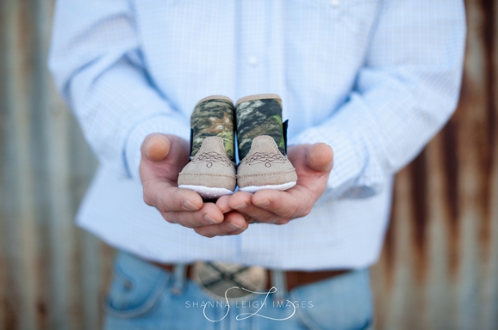 An expectant father holding tiny baby western boots.