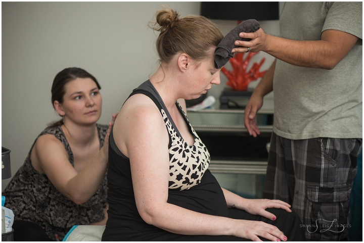 A mother laboring on a birth ball while her partner and doula assist at Fort Worth Birthing and Wellness Center. Fort Worth birth photography by Shanna Leigh Images.